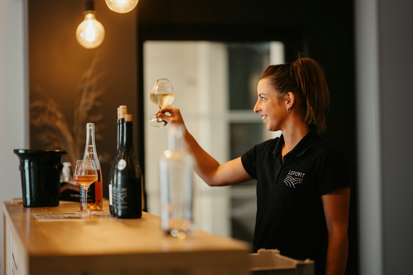 Winery staff examines a glass of white wine.